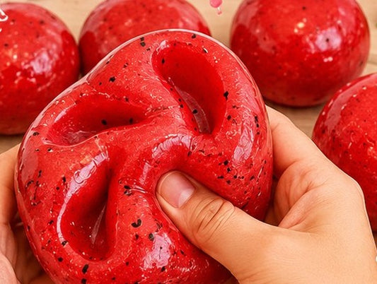 Red watermelon slow-rise squishy ball being squeezed by hand